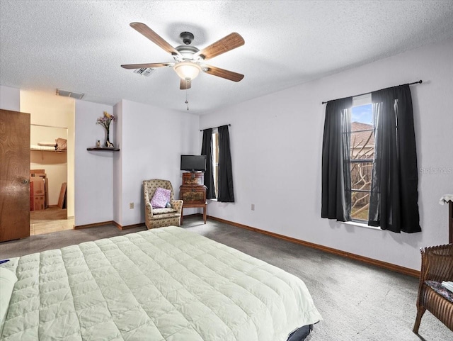 bedroom featuring dark colored carpet, ceiling fan, a spacious closet, and a textured ceiling