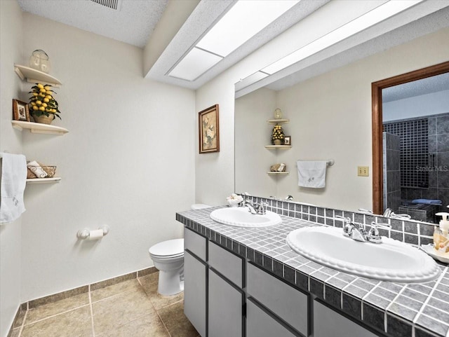 bathroom featuring a textured ceiling, vanity, tiled shower, tile patterned flooring, and toilet