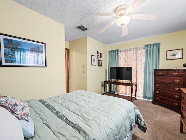 carpeted bedroom with ceiling fan and a textured ceiling