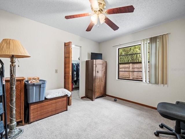 living area featuring ceiling fan, carpet floors, and a textured ceiling