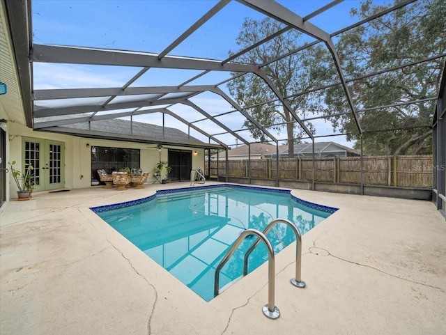 view of swimming pool featuring glass enclosure, a patio area, and french doors