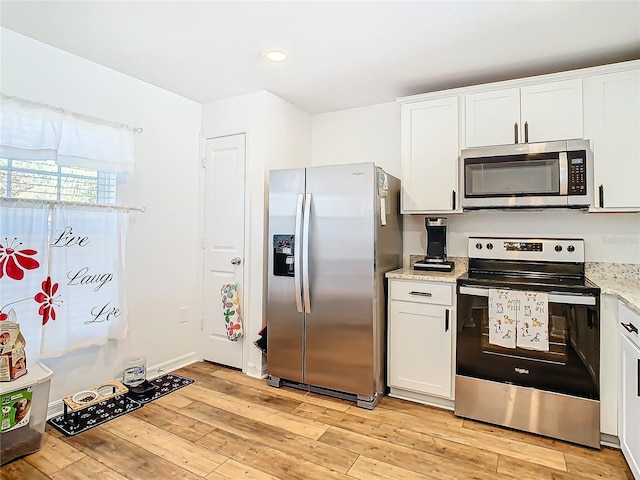 kitchen with light stone countertops, white cabinetry, appliances with stainless steel finishes, and light wood-type flooring