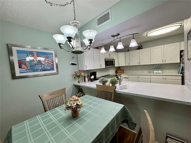 kitchen with sink, an inviting chandelier, decorative light fixtures, decorative backsplash, and white cabinets