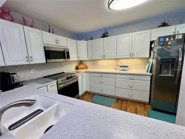 kitchen featuring white cabinets, appliances with stainless steel finishes, sink, and hardwood / wood-style floors