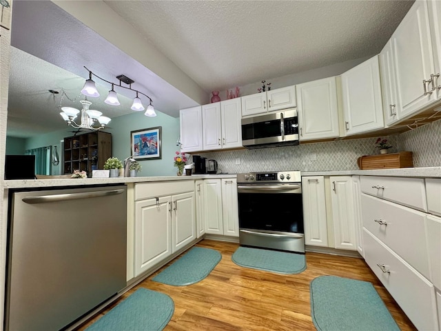 kitchen with white cabinetry, light hardwood / wood-style flooring, a chandelier, decorative backsplash, and appliances with stainless steel finishes