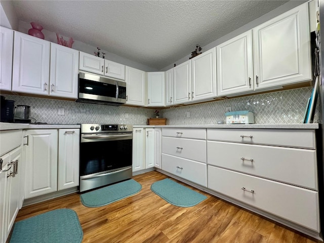 kitchen featuring white cabinetry, light hardwood / wood-style flooring, stainless steel appliances, and a textured ceiling