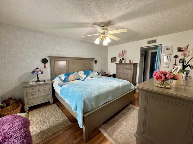 bedroom featuring ceiling fan, wood-type flooring, and a textured ceiling