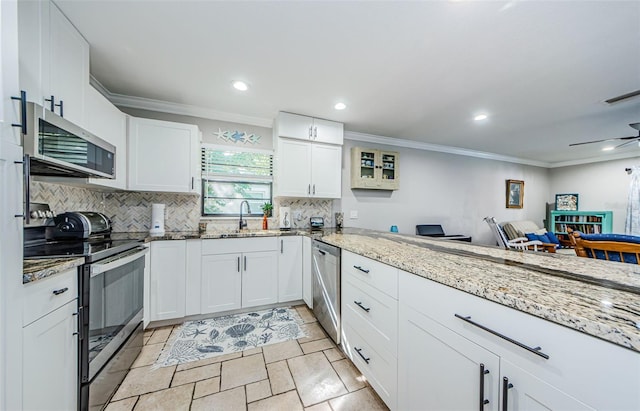 kitchen with white cabinets, stainless steel appliances, light stone counters, and sink