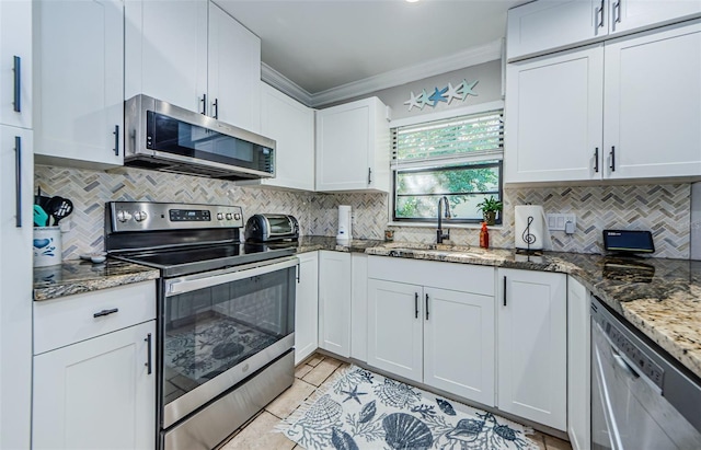 kitchen featuring appliances with stainless steel finishes, white cabinetry, dark stone counters, and sink