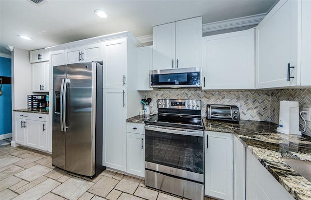 kitchen with white cabinets, backsplash, stainless steel appliances, and dark stone countertops