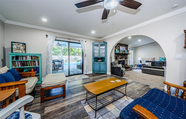 living room featuring a fireplace, wood-type flooring, ceiling fan, and crown molding