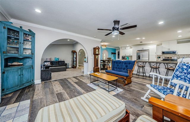 living room featuring dark hardwood / wood-style flooring, ceiling fan, and ornamental molding