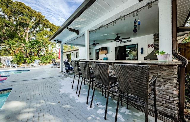 view of patio / terrace featuring ceiling fan and a bar