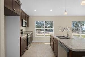 kitchen with a healthy amount of sunlight, sink, stainless steel appliances, and decorative light fixtures