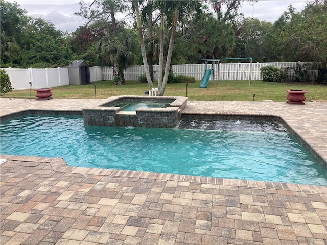 view of pool with a lawn, a playground, a storage shed, an in ground hot tub, and a patio