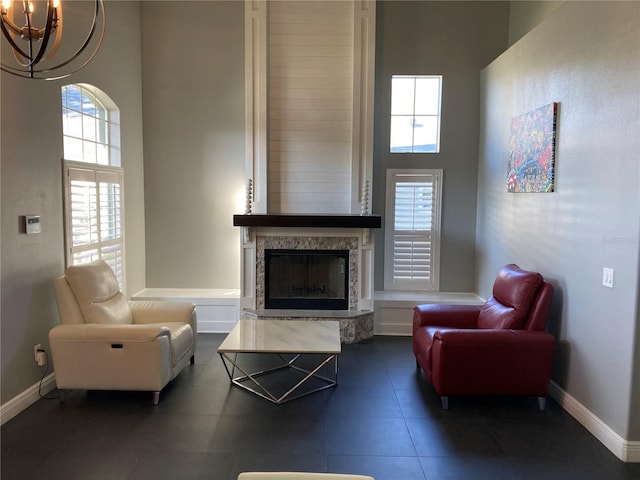 living room with a wealth of natural light, a large fireplace, a high ceiling, and a notable chandelier