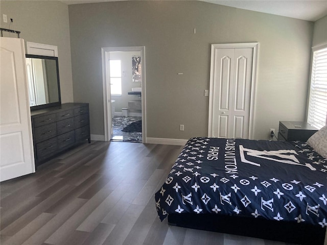 bedroom featuring connected bathroom, a closet, dark hardwood / wood-style flooring, and vaulted ceiling