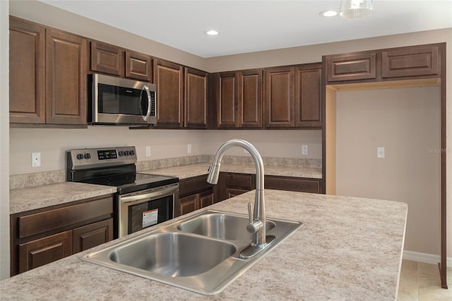 kitchen featuring dark brown cabinets, light tile patterned floors, sink, and appliances with stainless steel finishes