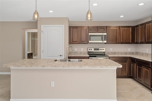 kitchen with hanging light fixtures, a kitchen island with sink, sink, and appliances with stainless steel finishes