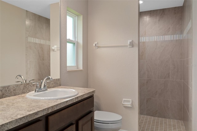 bathroom featuring vanity, toilet, and a tile shower