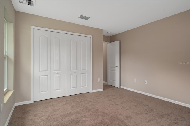 unfurnished bedroom featuring a closet and light colored carpet