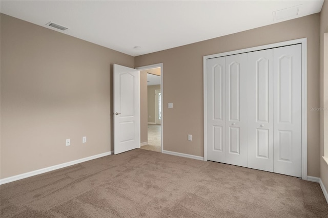 unfurnished bedroom featuring light carpet and a closet