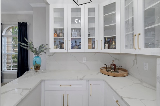 kitchen with decorative backsplash, white cabinetry, light stone countertops, and crown molding