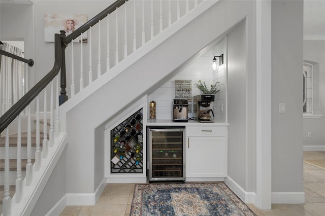 bar featuring white cabinets, wine cooler, crown molding, and light tile patterned flooring