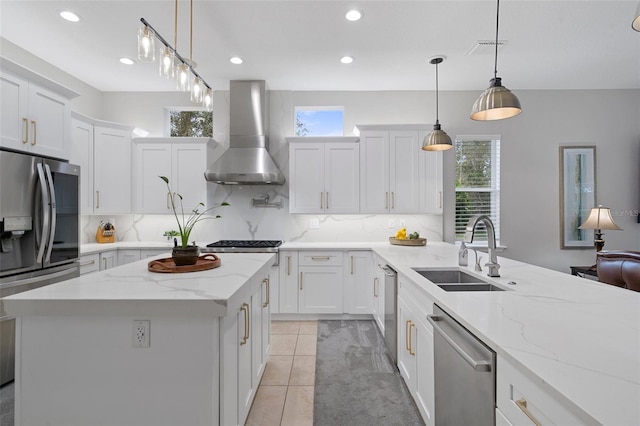 kitchen with sink, hanging light fixtures, wall chimney exhaust hood, light tile patterned floors, and stainless steel appliances