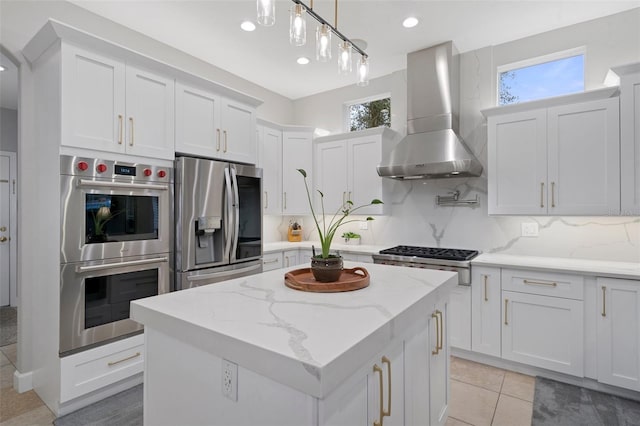 kitchen featuring white cabinets, stainless steel appliances, plenty of natural light, and wall chimney range hood