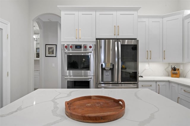 kitchen with white cabinetry, light stone countertops, tasteful backsplash, and stainless steel appliances