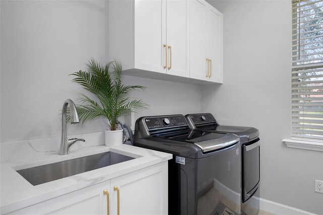 clothes washing area with washer and dryer, cabinets, and sink