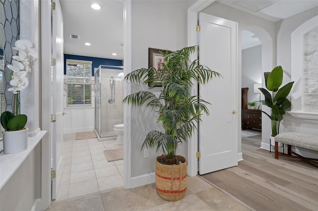 bathroom with hardwood / wood-style floors, toilet, and a shower with shower door