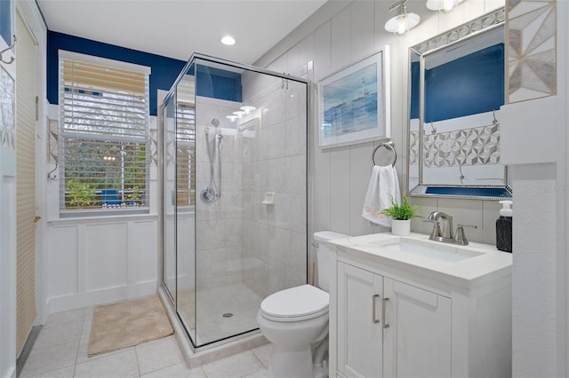 bathroom featuring tile patterned flooring, vanity, a shower with shower door, and toilet