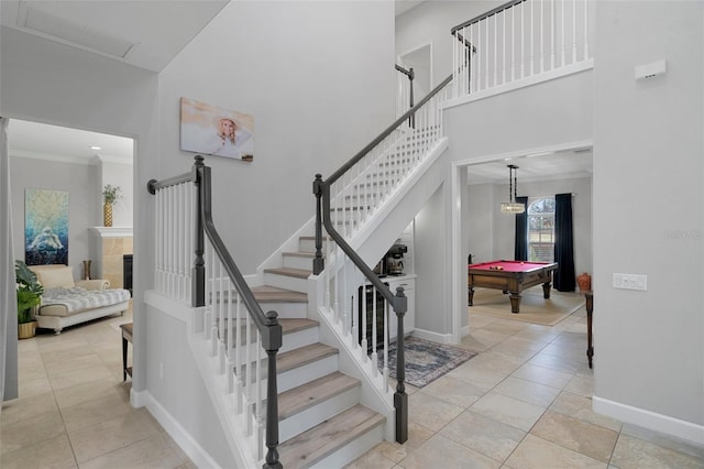 stairway with tile patterned floors, a tiled fireplace, ornamental molding, and billiards