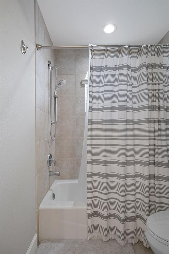 bathroom with shower / bath combination with curtain and toilet