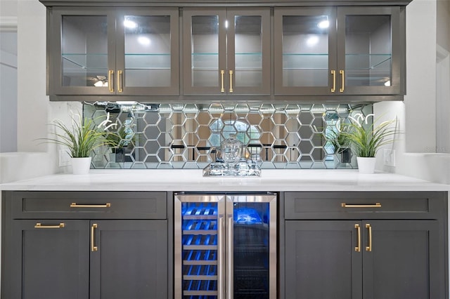 bar featuring decorative backsplash, wine cooler, and gray cabinetry