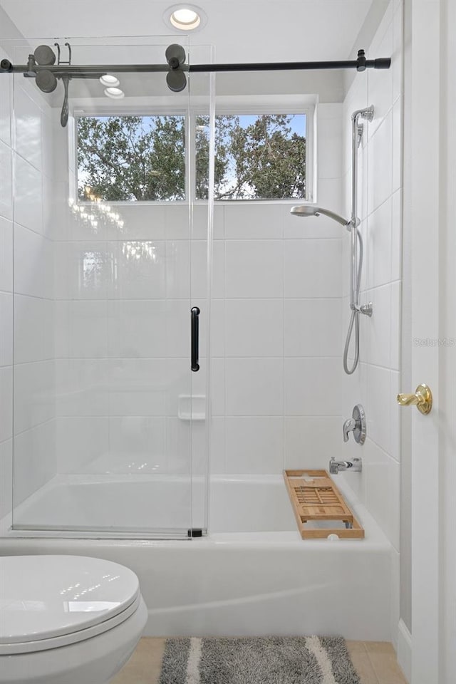 bathroom with tile patterned floors, bath / shower combo with glass door, and toilet