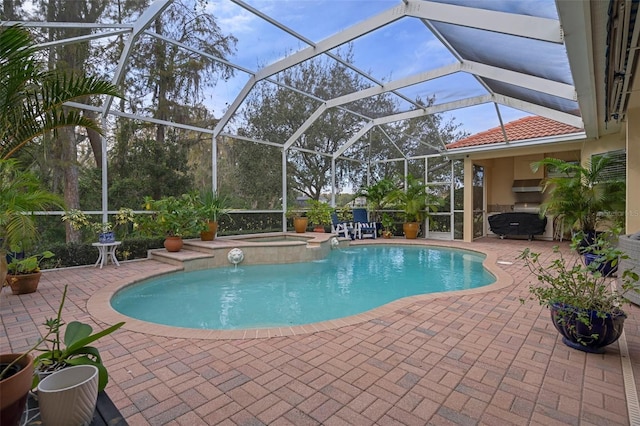 view of pool featuring glass enclosure, an in ground hot tub, and a patio