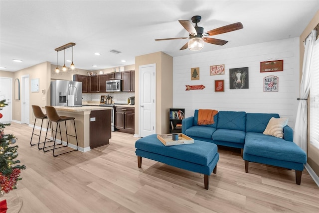 living room featuring ceiling fan and light hardwood / wood-style floors