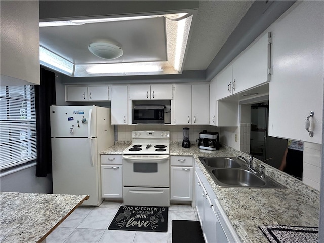 kitchen featuring white cabinetry, sink, white appliances, a tray ceiling, and light tile patterned floors