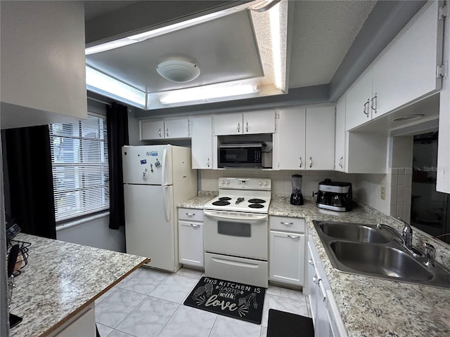 kitchen featuring sink, light tile patterned floors, white appliances, a tray ceiling, and white cabinets