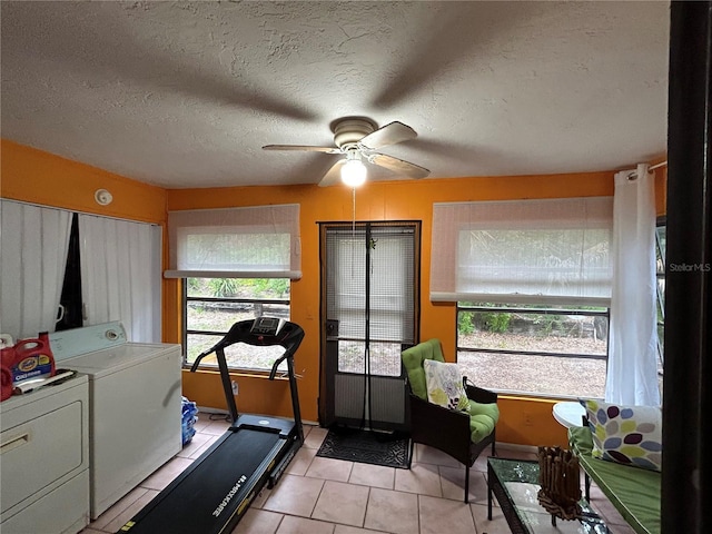 exercise room featuring separate washer and dryer, ceiling fan, light tile patterned floors, and a textured ceiling