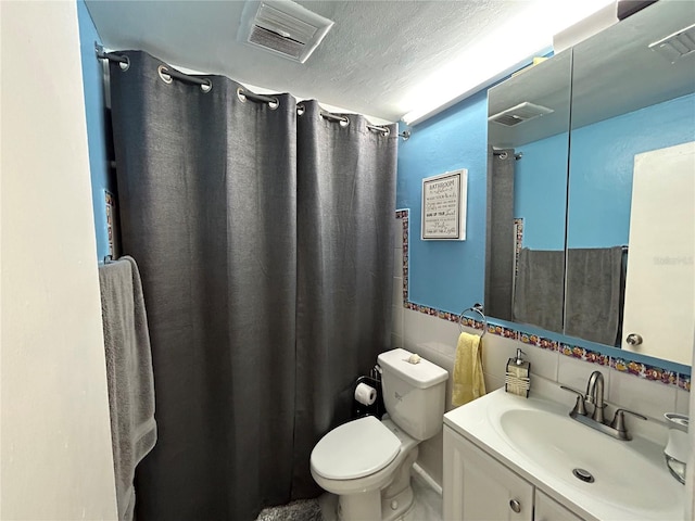 bathroom with backsplash, a textured ceiling, toilet, vanity, and tile walls