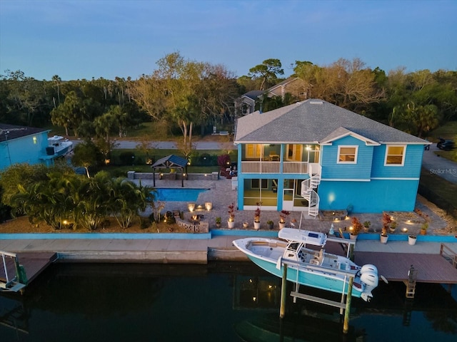 back house at dusk with a balcony and a water view