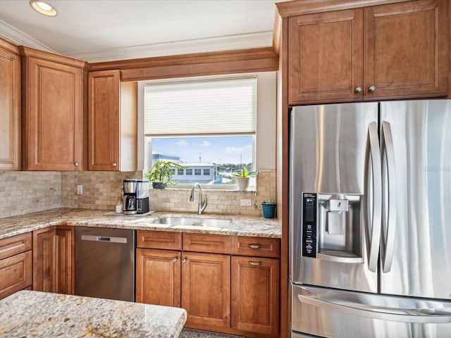 kitchen with appliances with stainless steel finishes, tasteful backsplash, light stone counters, and sink