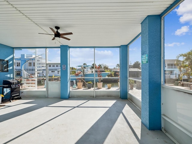 sunroom featuring ceiling fan and a water view