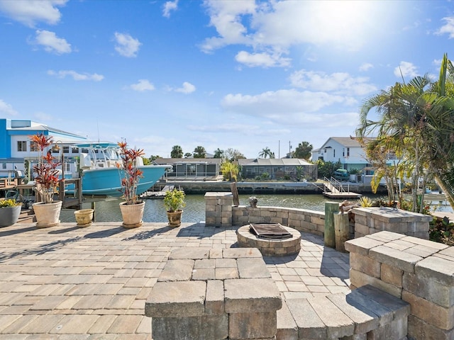 view of patio featuring a boat dock, a water view, and an outdoor fire pit