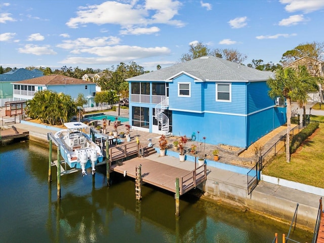 back of property featuring a patio area, a sunroom, and a water view