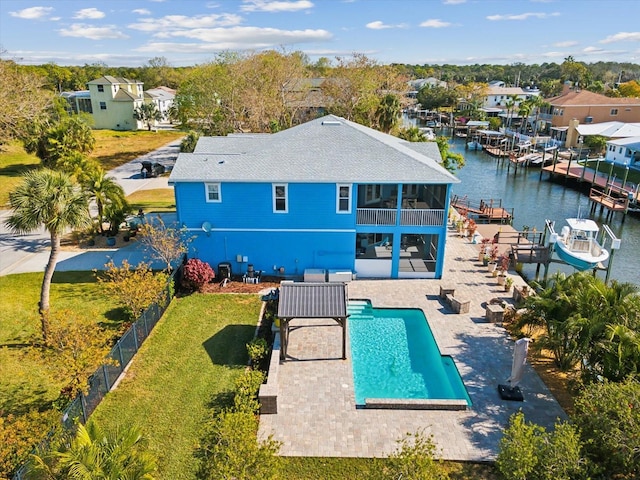 exterior space featuring a water view, a patio area, a sunroom, a yard, and a fenced in pool